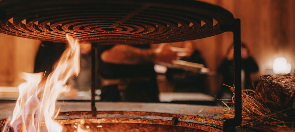 Menschen beim gemeinsamen Grillen in einer offenen Feuerküche